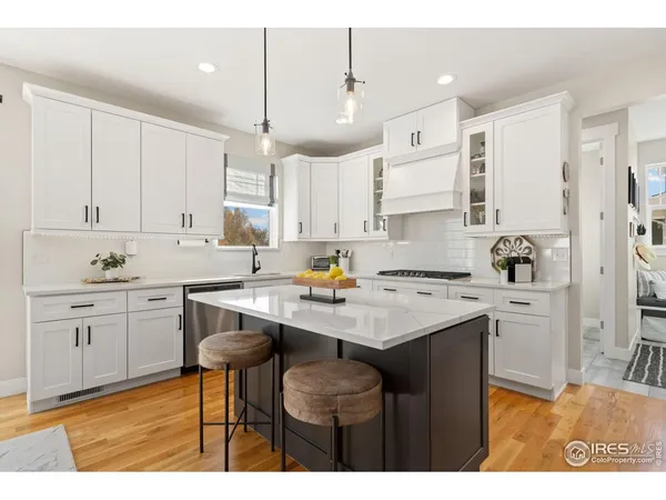 a kitchen with a sink a stove a refrigerator and white cabinets with wooden floor