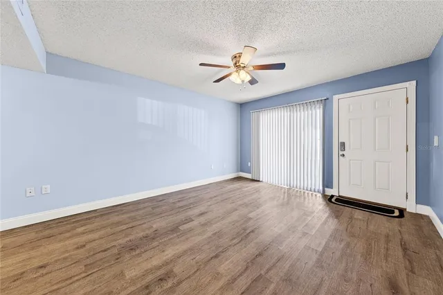 a view of empty room with wooden floor and fan