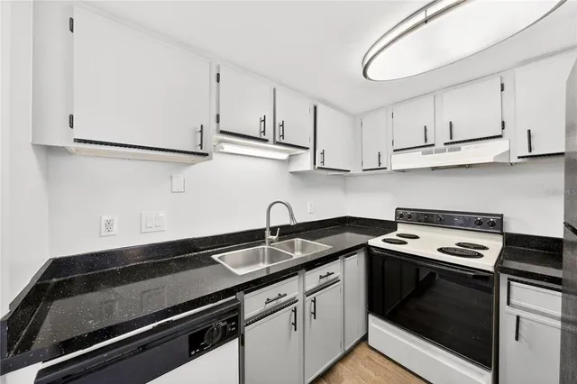 a kitchen with granite countertop white cabinets and black appliances