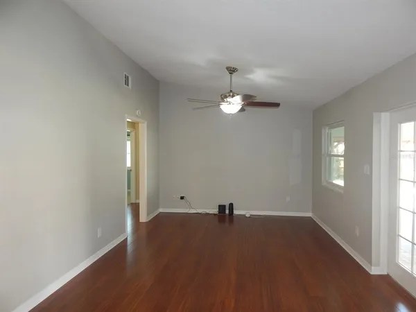 an empty room with wooden floor and windows