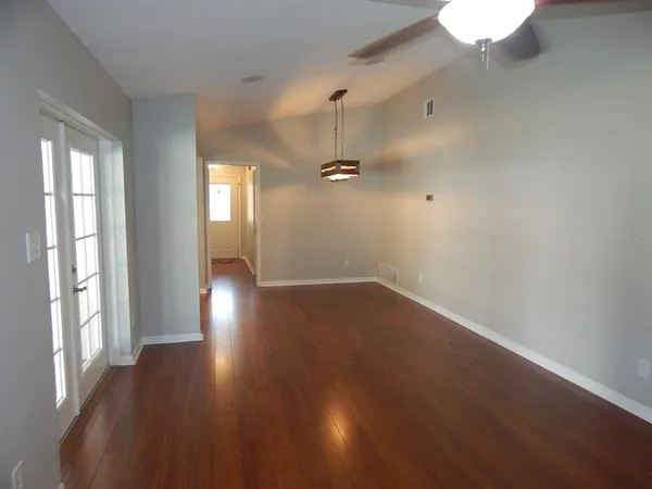 an empty room with wooden floor and windows