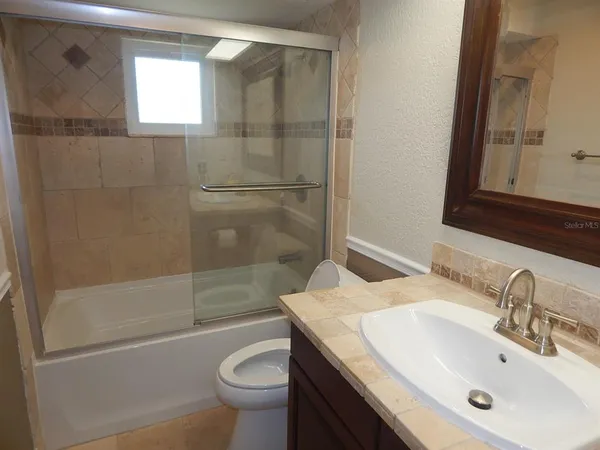 a bathroom with a granite countertop sink toilet and shower