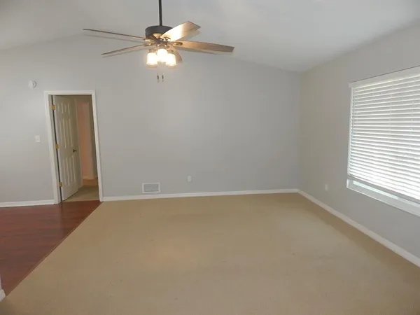 an empty room with a window and a fan