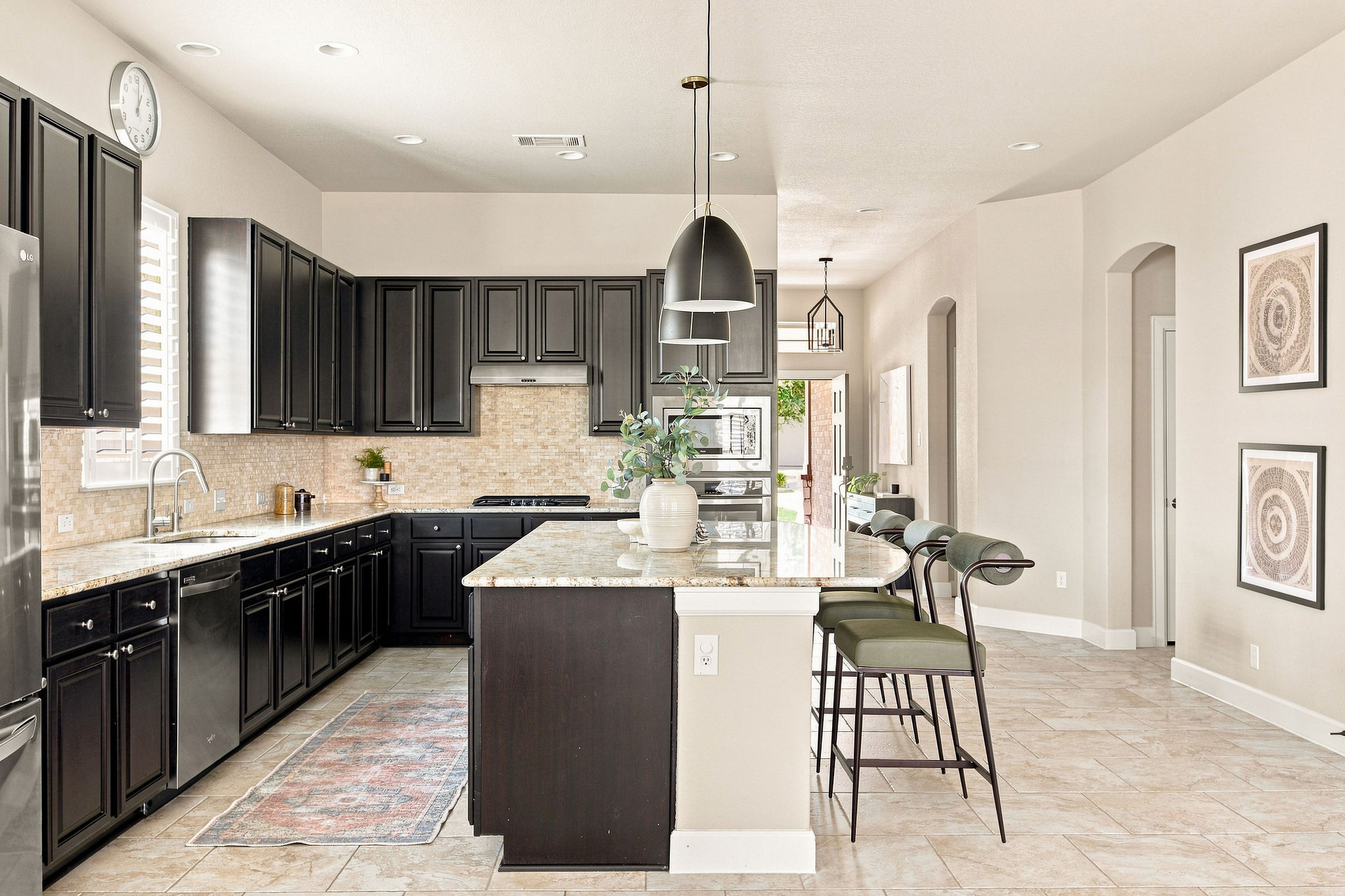 6100 Gunnison Turn Road Austin, TX 78738 - Photo 19 of 34 Dark cabinetry beautifully contrasts with light stone countertops in this modern kitchen layout.
