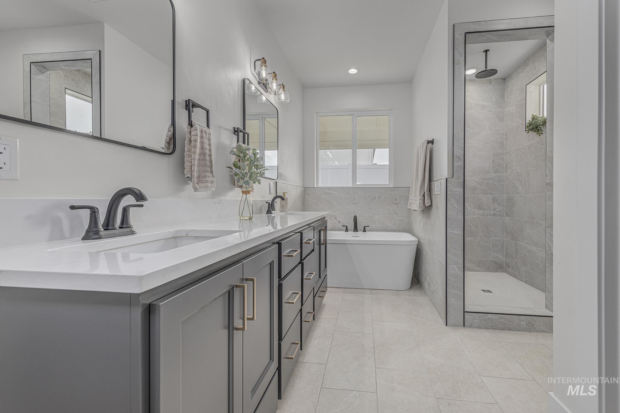 2810 Cypress Point Payette, ID 83661 - Photo 17 of 46 Bathroom featuring tile walls, double vanity, plenty of natural light, a freestanding tub, and light tile patterned flooring