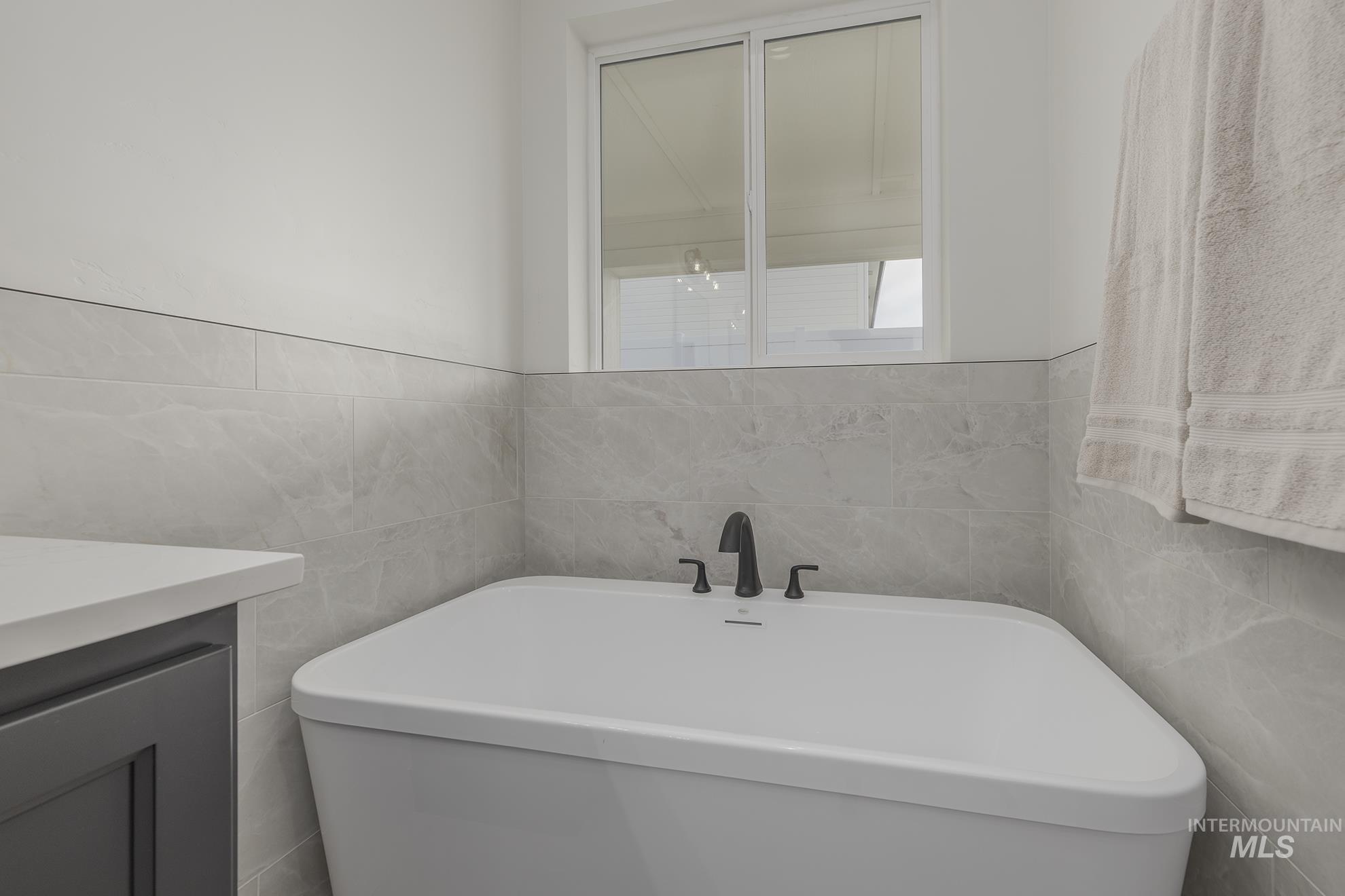 2810 Cypress Point Payette, ID 83661 - Photo 20 of 46 Full bathroom featuring tile walls, a soaking tub, and vanity