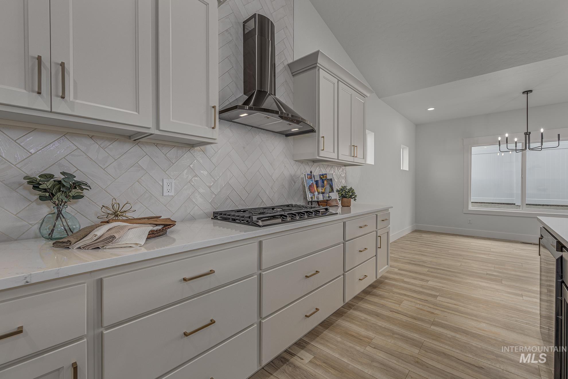 2810 Cypress Point Payette, ID 83661 - Photo 4 of 46 Kitchen featuring wall chimney range hood, light wood-style flooring, backsplash, pendant lighting, and light stone counters