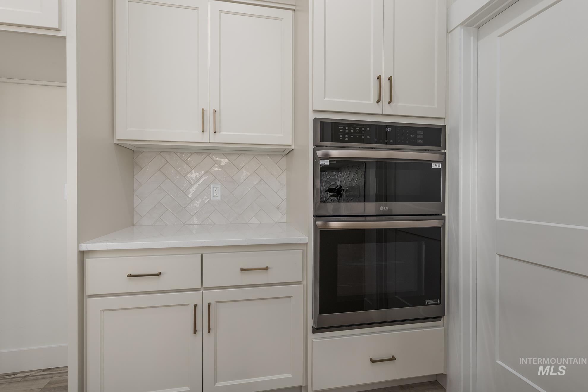 2810 Cypress Point Payette, ID 83661 - Photo 6 of 46 Kitchen featuring stainless steel double oven, white cabinets, tasteful backsplash, and light stone counters