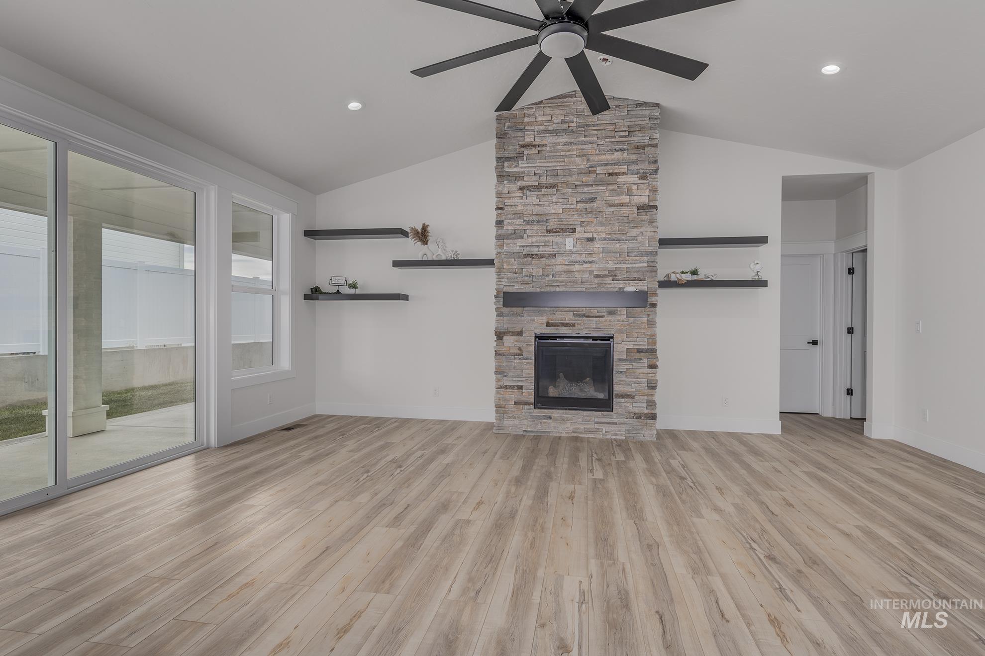 2810 Cypress Point Payette, ID 83661 - Photo 7 of 46 Unfurnished living room with vaulted ceiling, light wood finished floors, ceiling fan, a fireplace, and recessed lighting