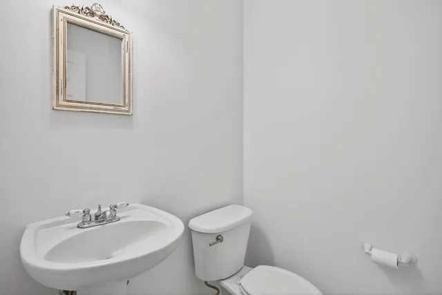 a bathroom with a toilet a sink and mirror