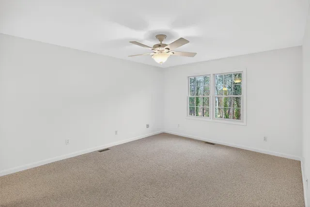 an empty room with a window and a ceiling fan