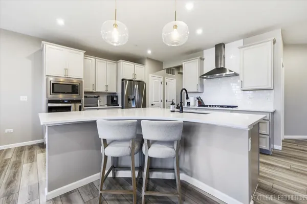 a kitchen with stainless steel appliances a dining table chairs refrigerator and cabinets