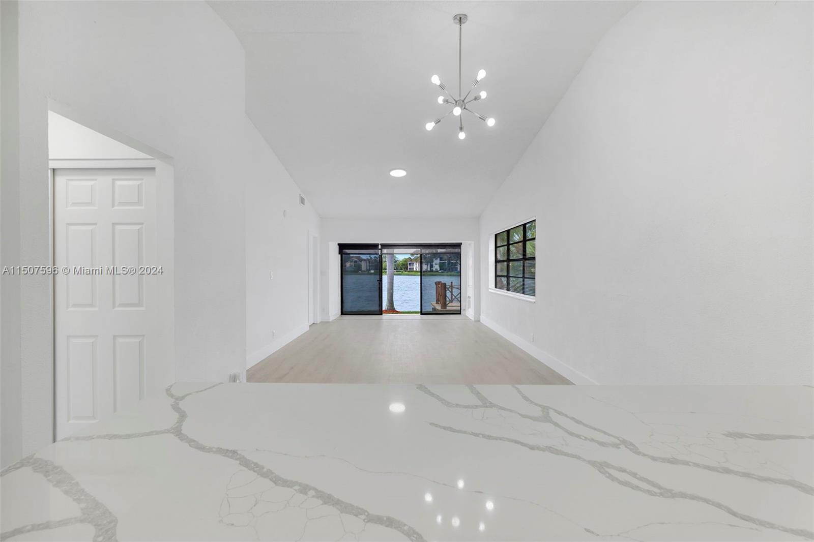 645 Banks Road Margate, FL 33063 - Photo 11 of 38 a view of an empty room with chandelier and kitchen view