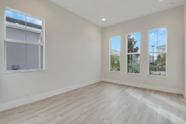 a view of an empty room with a window and wooden floor