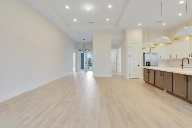 a view of a kitchen with kitchen island a sink wooden floor and a refrigerator