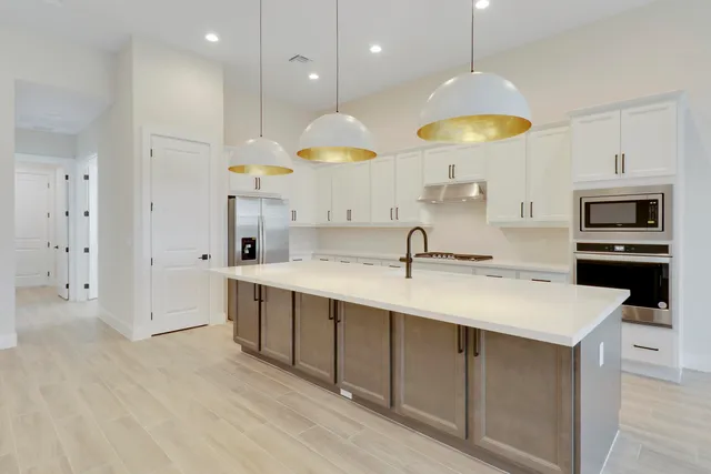 a kitchen with stainless steel appliances a stove a sink a center island and cabinets