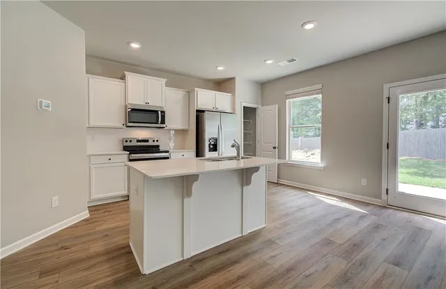 a kitchen with kitchen island granite countertop a sink cabinets and wooden floor