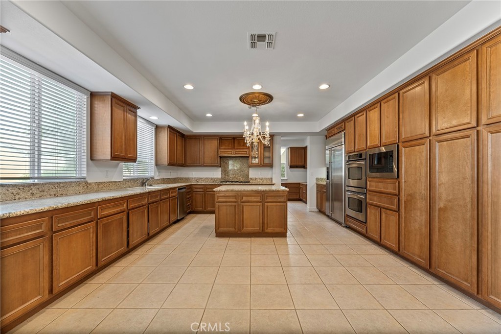 6360 Day Lily Court Rancho Cucamonga, CA 91737 - Photo 17 of 56 a large kitchen with stainless steel appliances kitchen island granite countertop a large counter top a stove a sink dishwasher a dining table and chairs with wooden floor