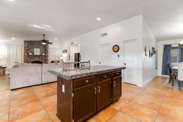 a kitchen with stainless steel appliances granite countertop a stove top oven a sink a counter top space and living room view