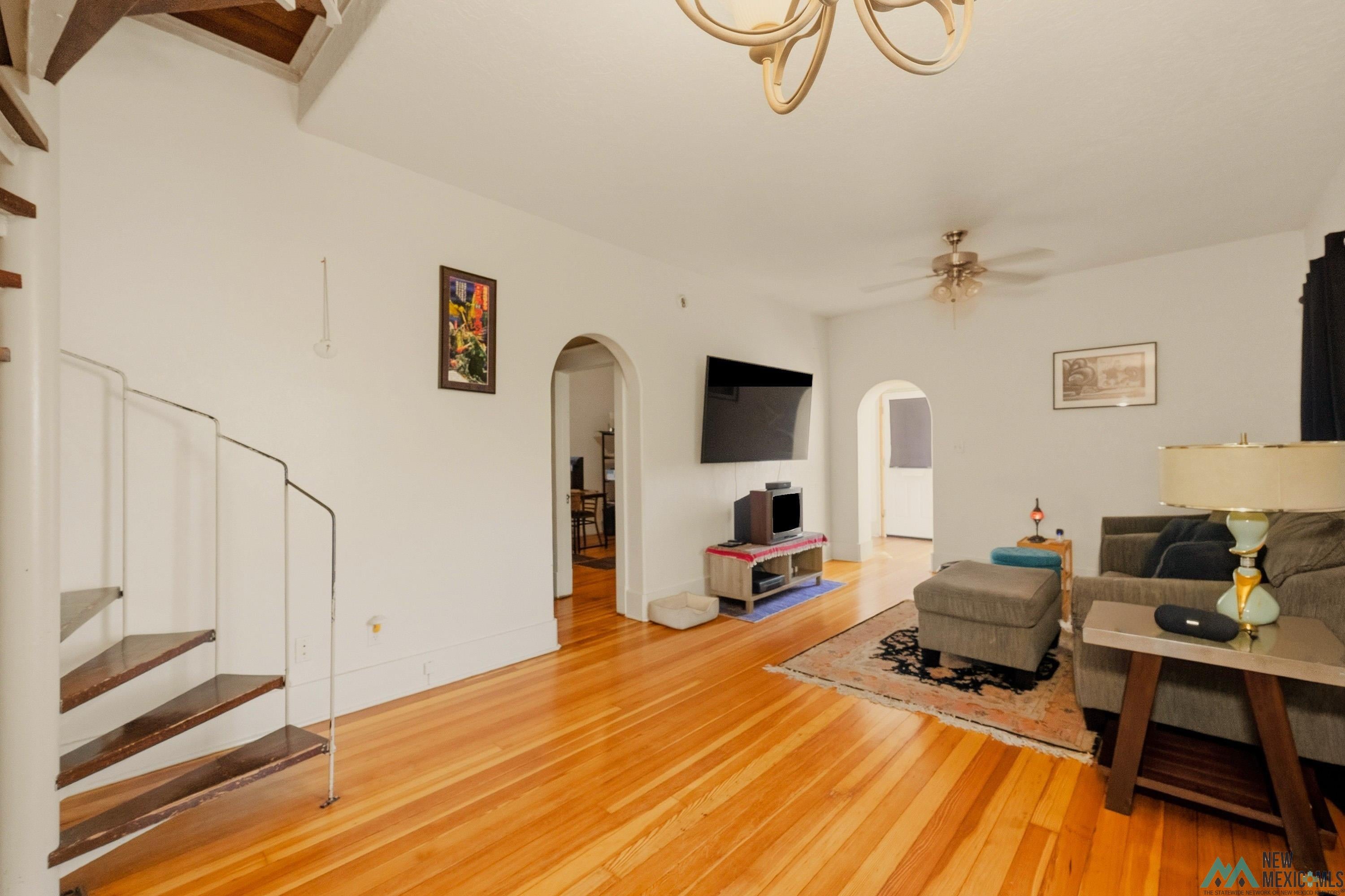 1026 South 5th Street Raton, NM 87740 - Photo 5 of 33 Warm wood-finish flooring throughout, complemented by a spiral staircase with dark wood treads and white metal railing
