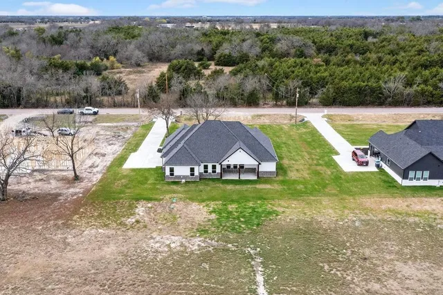 an aerial view of a house with pool and a yard