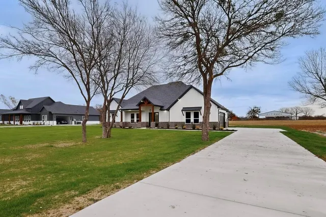 a front view of a house with a yard and trees