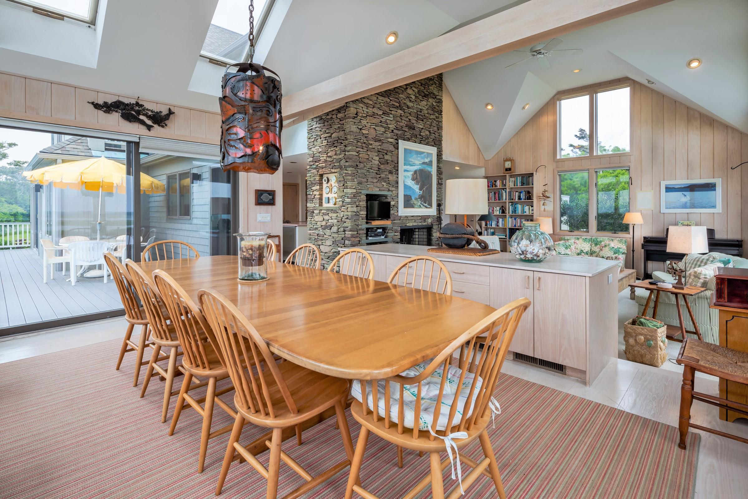 2-7 Skunk Bluff Orleans, MA 02653 - Photo 19 of 80 a dining area with a table chairs and a floor to ceiling window