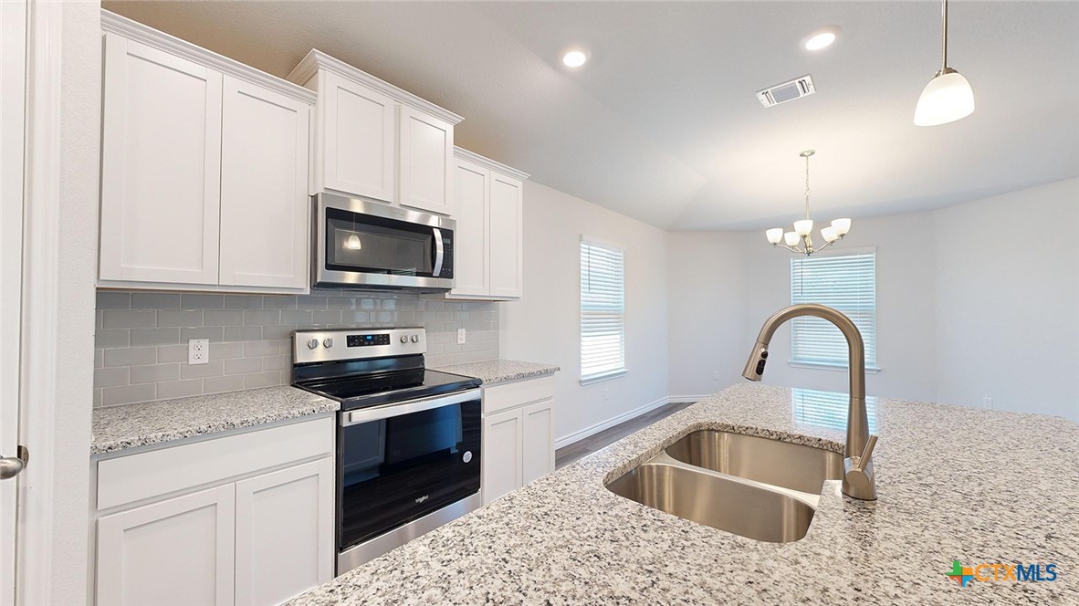 2136 Buckner Street Nolanville, TX 76559 - Photo 5 of 33 a kitchen with stainless steel appliances granite countertop a stove a sink and a microwave