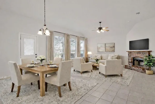 a view of an empty room with chandelier fan and fire place