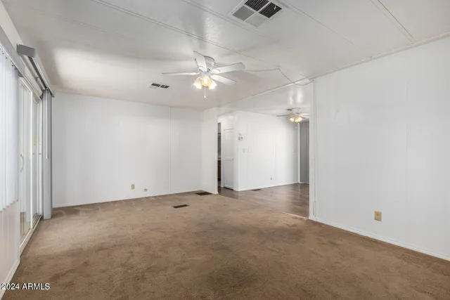 an empty room with a ceiling fan and a window