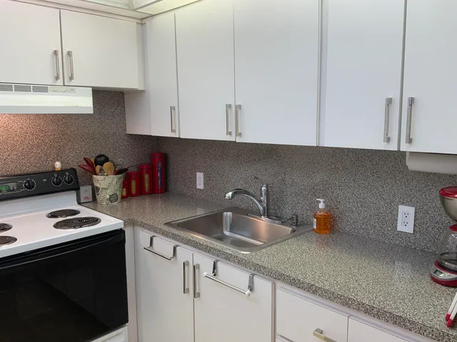a kitchen with stainless steel appliances granite countertop a sink a stove and white cabinets