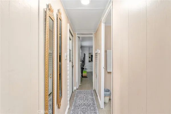 a view of a hallway with wooden floor and a bathroom