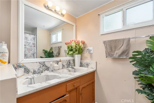 a bathroom with a granite countertop sink a mirror and a shower