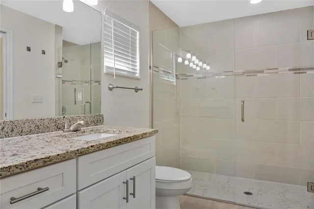 a bathroom with a granite countertop sink a toilet and shower