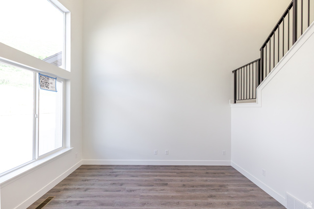 5287 South Acacia Drive, Unit 714 Mapleton, UT 84664 - Photo 10 of 21 Room featuring soaring ceilings, wood-finish flooring, a contemporary staircase with black wrought iron railing, expansive windows, and white trim