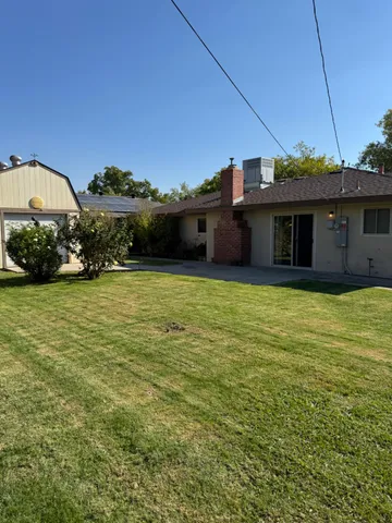 a view of a yard in front of a house with a large tree
