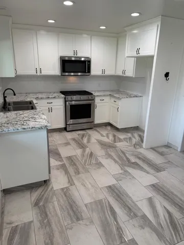 a kitchen with stainless steel appliances granite countertop a stove a sink and a refrigerator