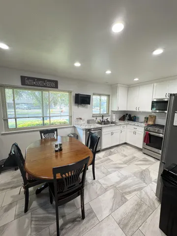 a kitchen with a dining table chairs and refrigerator