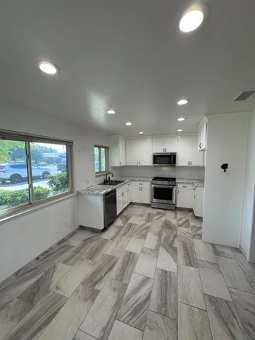 a large white kitchen with a stove top oven a sink and dishwasher a refrigerator with wooden floor