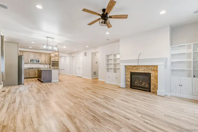 an empty room with kitchen and fireplace