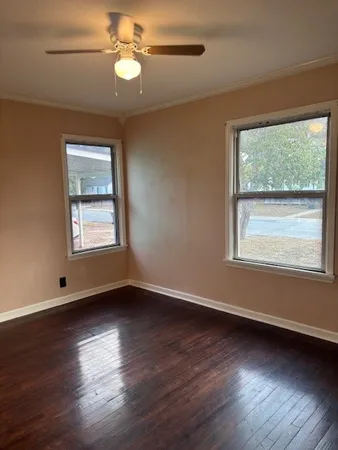 a view of an empty room with wooden floor and a window
