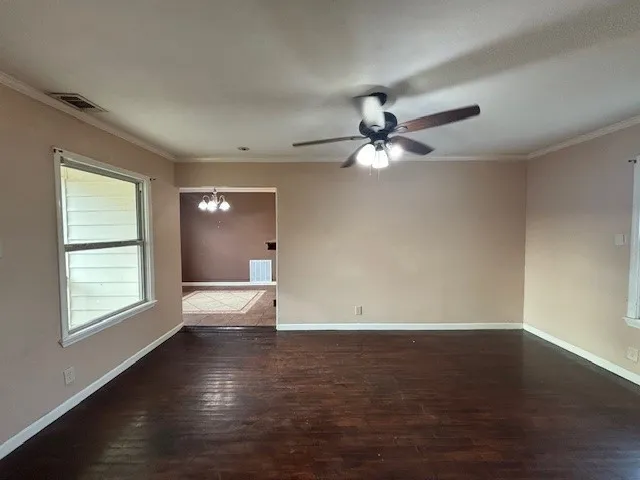 an empty room with wooden floor chandelier fan and windows