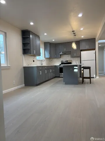 a large kitchen with stainless steel appliances kitchen island granite countertop a sink a stove and cabinets