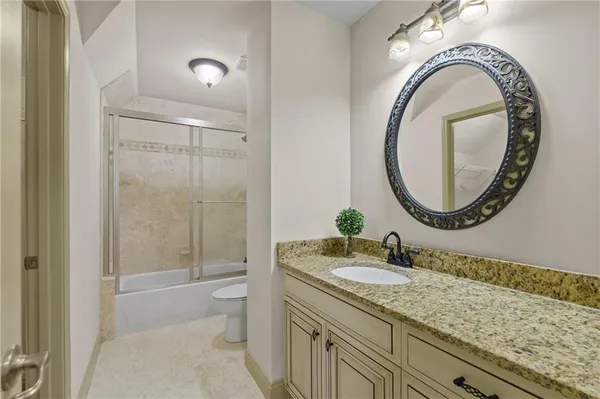 a bathroom with a granite countertop toilet a sink and a mirror