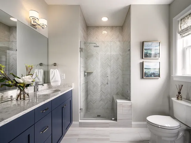 a bathroom with a granite countertop sink a toilet a mirror and shower