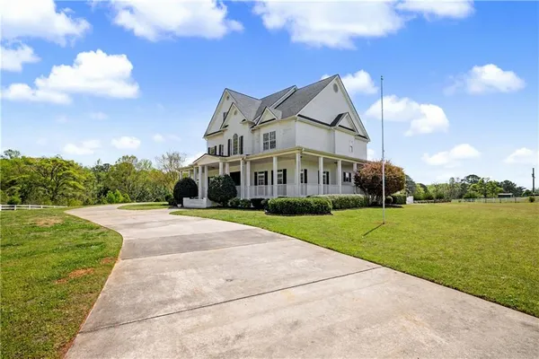 a front view of a house with a big yard and large trees
