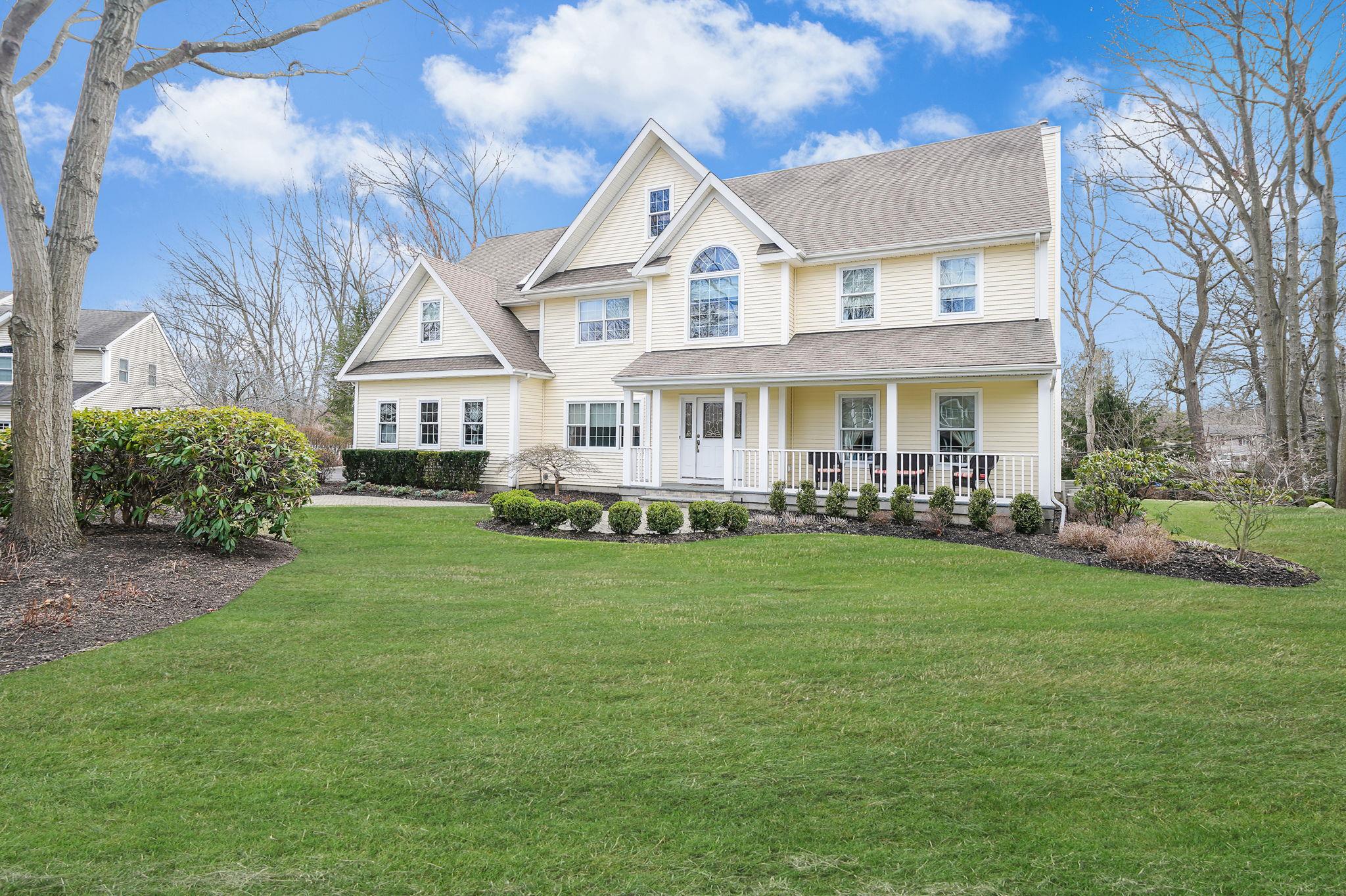 View of front of house featuring a shingled roof, a front yard, and covered porch