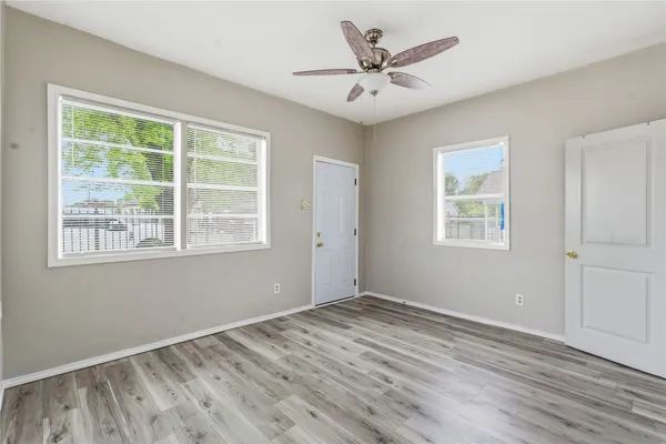 a view of an empty room with wooden floor and a window