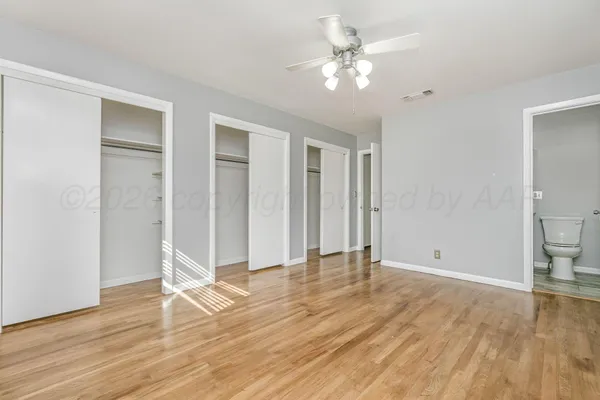 an empty room with wooden floor and ceiling fan