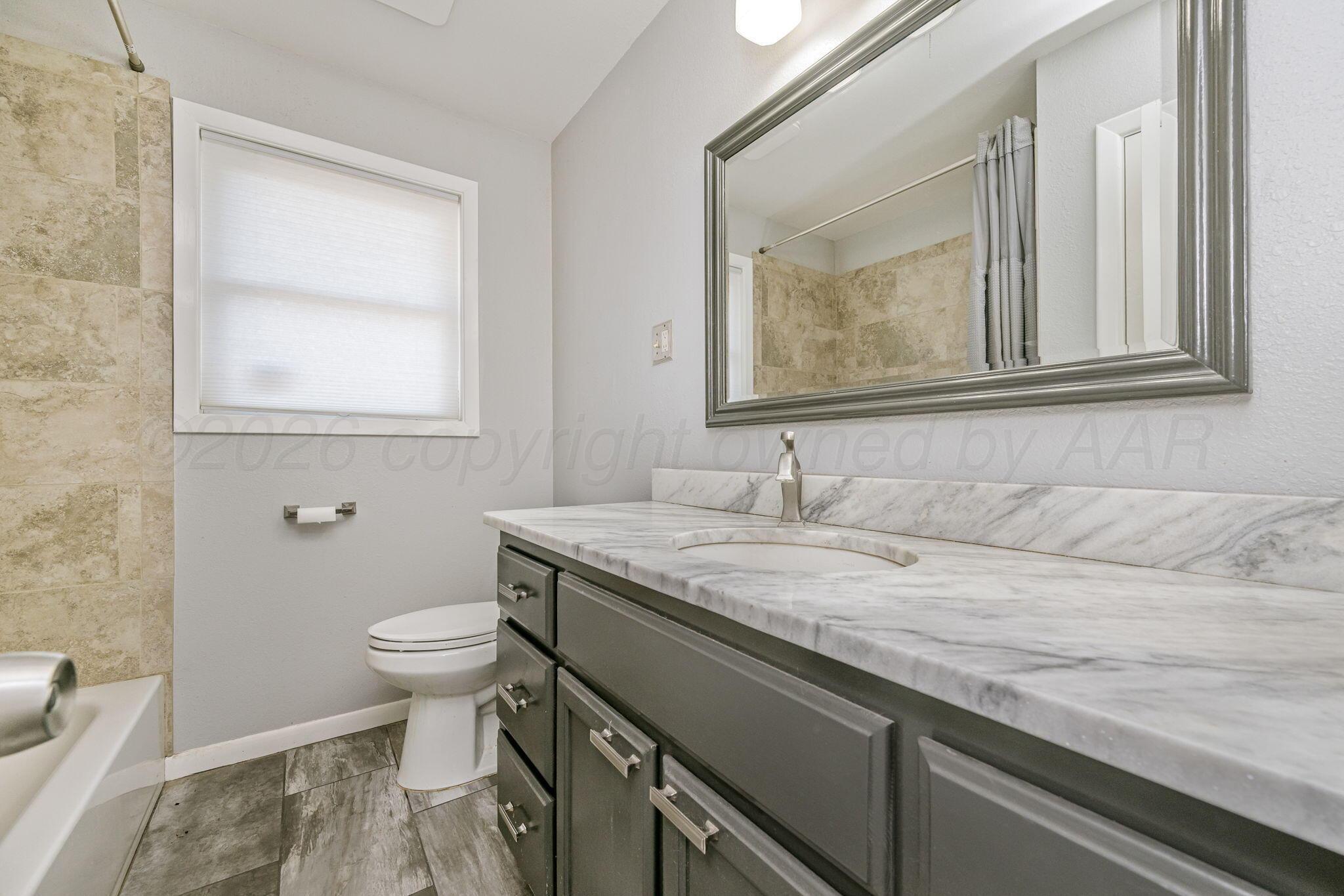 4305 Omaha Avenue Amarillo, TX 79106 - Photo 16 of 20 a bathroom with a granite countertop sink a toilet and a mirror